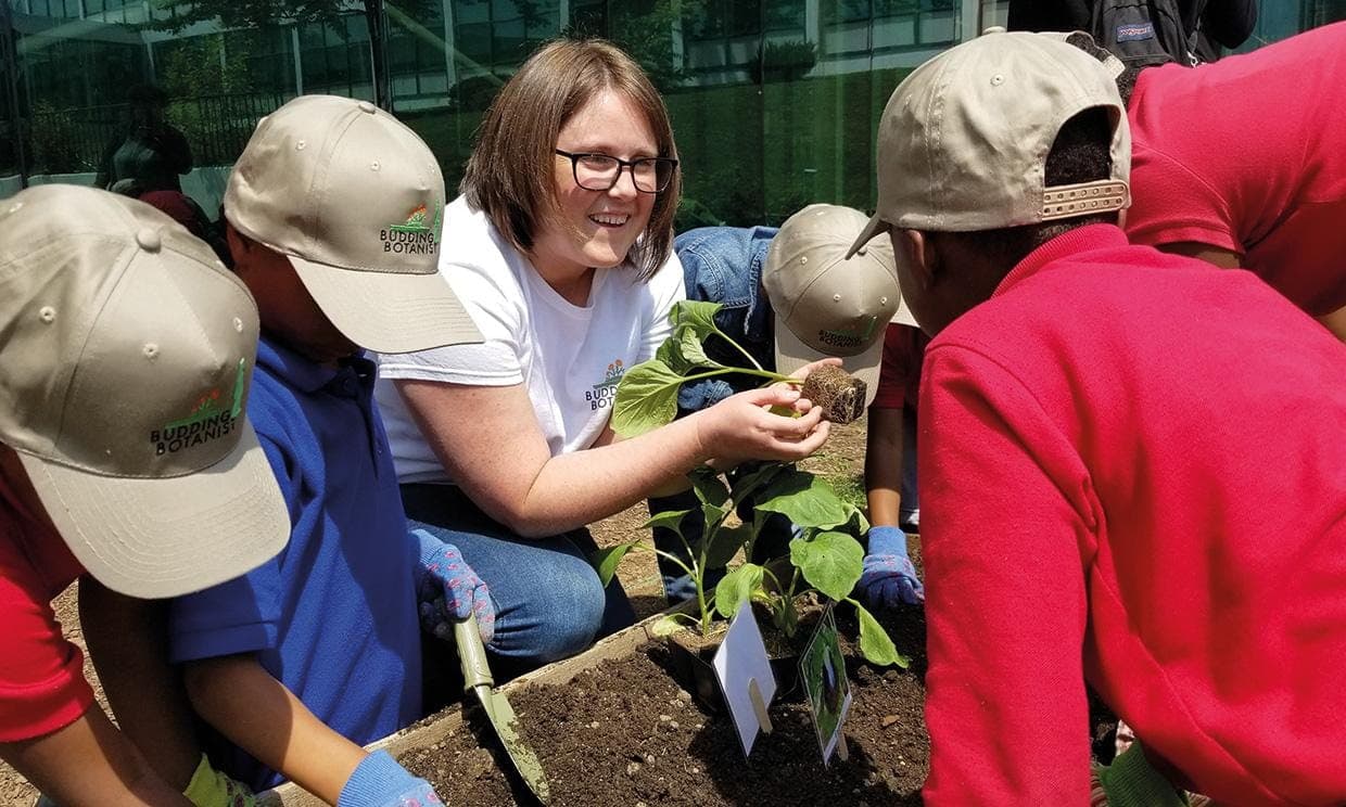 Chidren gathered around smiling girl holding plant